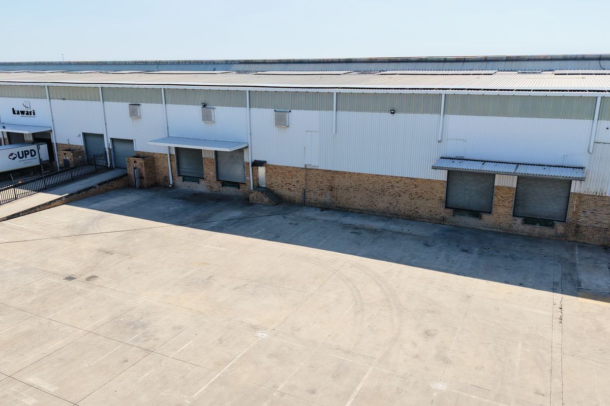 Aerial view of an industrial warehouse facility featuring multiple roller shutter loading bays, a large concrete yard, and durable brick and metal cladding construction.