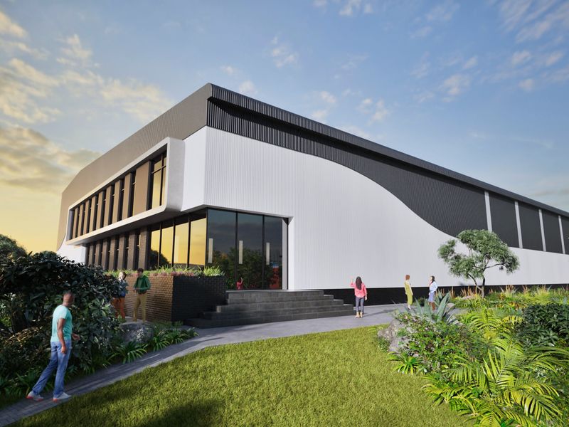 Modern industrial building exterior featuring sleek corrugated metal cladding, expansive glass facade, and landscaped entrance area.