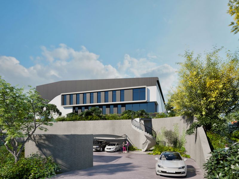 Modern industrial property featuring a sleek facade, large windows, a spiral staircase, and a paved driveway with covered parking.
