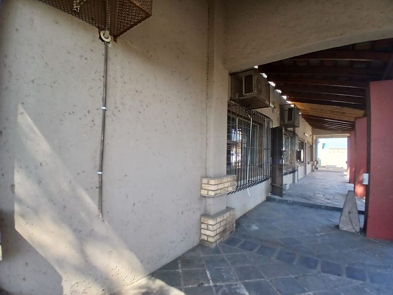 A covered outdoor patio area featuring stone flooring, exposed timber rafters, and security-fitted windows, suitable for industrial or commercial use.