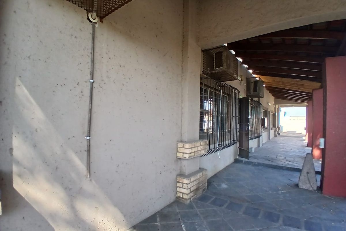 A covered outdoor patio area featuring stone flooring, exposed timber rafters, and security-fitted windows, suitable for industrial or commercial use.