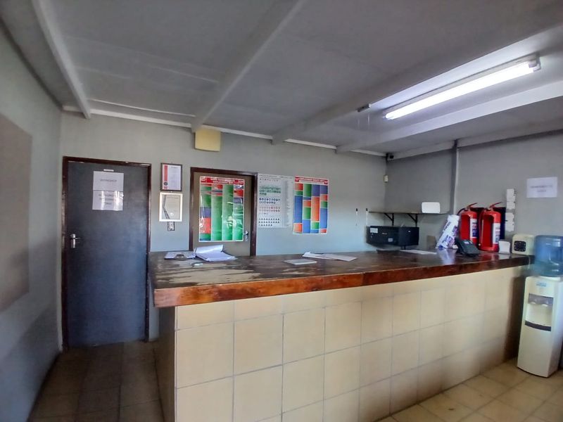 Functional industrial utility or reception space featuring a built-in service counter, tiled finishes, and overhead fluorescent lighting.