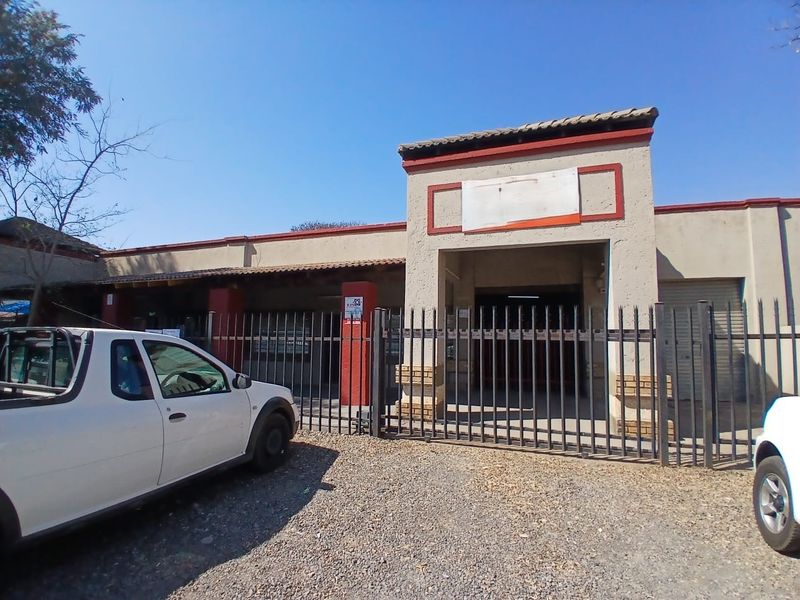 Front elevation of an industrial property featuring a gated entrance, security fencing, and a roller shutter door access point.