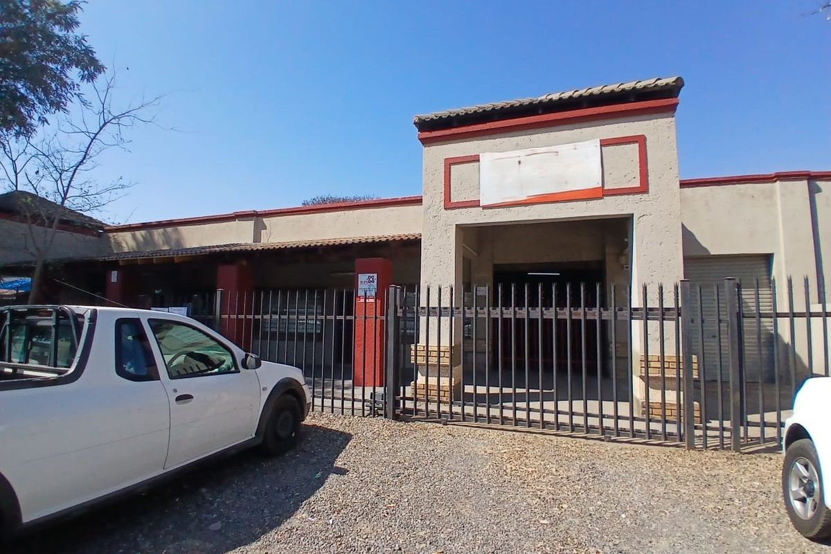 Front elevation of an industrial property featuring a gated entrance, security fencing, and a roller shutter door access point.