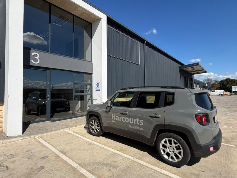 Modern industrial unit exterior featuring metal cladding, large glass entrance facade, and dedicated paved parking space.