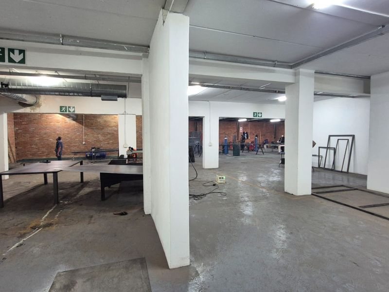 Spacious industrial utility area featuring exposed ducting, concrete flooring, and structural columns, suitable for workshop or storage use.