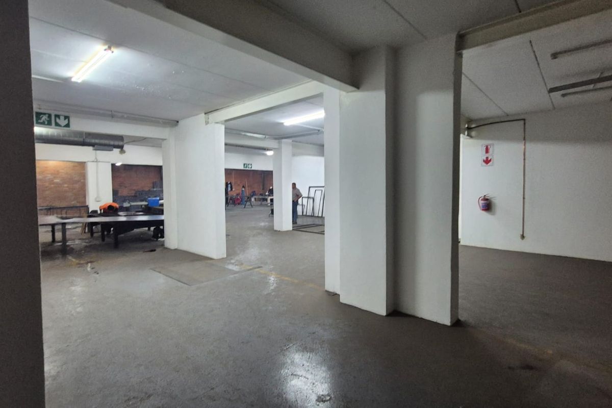 Spacious industrial utility area featuring concrete flooring, exposed ducting, and functional fluorescent lighting, suitable for workshop or storage operations.