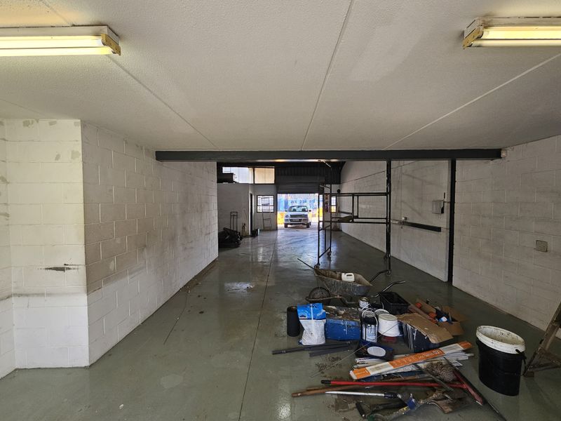 An open-plan industrial utility space featuring painted concrete block walls, a durable concrete floor, and overhead fluorescent lighting, suitable for workshop or storage use.