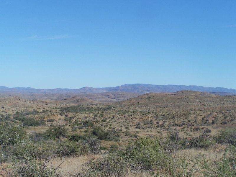 A panoramic view of the expansive arid landscape and rolling hills characteristic of the surrounding farm property.