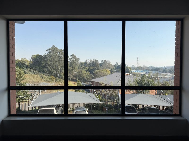 A clear view of the surrounding office park grounds and parking area, framed by a large window with a brick surround.