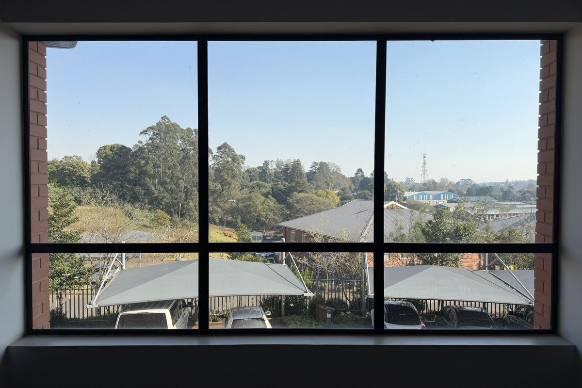 A clear view of the surrounding office park grounds and parking area, framed by a large window with a brick surround.
