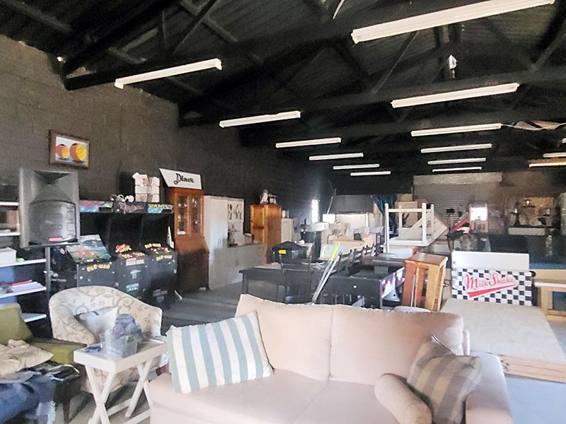 Spacious industrial utility area featuring exposed timber roof trusses, concrete block walls, and concrete flooring, suitable for storage or workshop use.