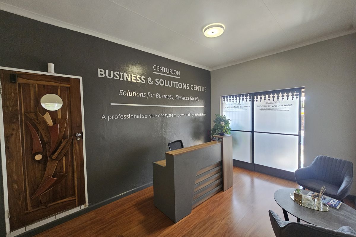 A professional office reception area featuring a modern desk, laminate flooring, and a decorative wooden door with a frosted glass entrance partition.
