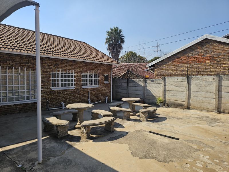 Rear exterior courtyard featuring brick building facade, concrete paving, and perimeter boundary walling.