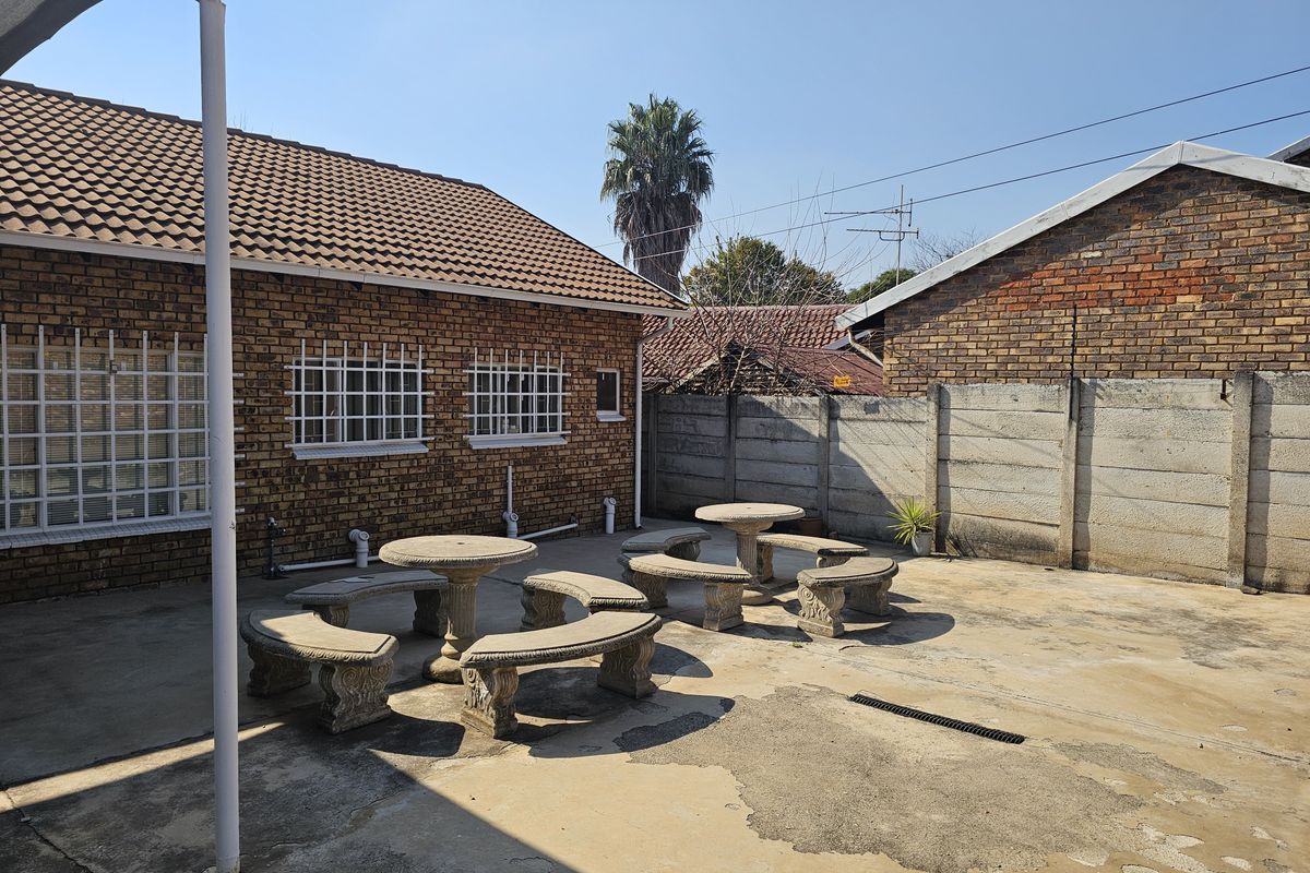 Rear exterior courtyard featuring brick building facade, concrete paving, and perimeter boundary walling.