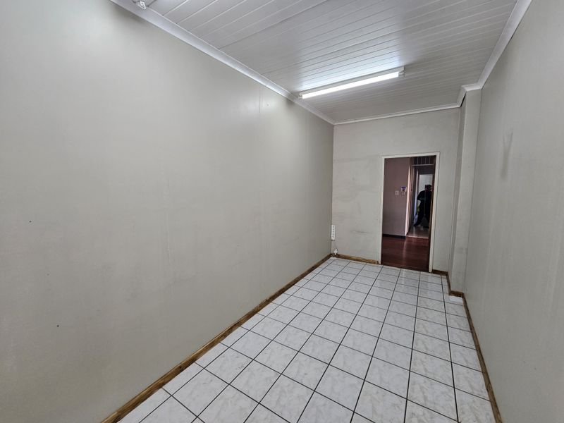 An empty office space featuring tiled flooring, tongue and groove ceiling, and fluorescent lighting, ready for customization or professional fit-out.