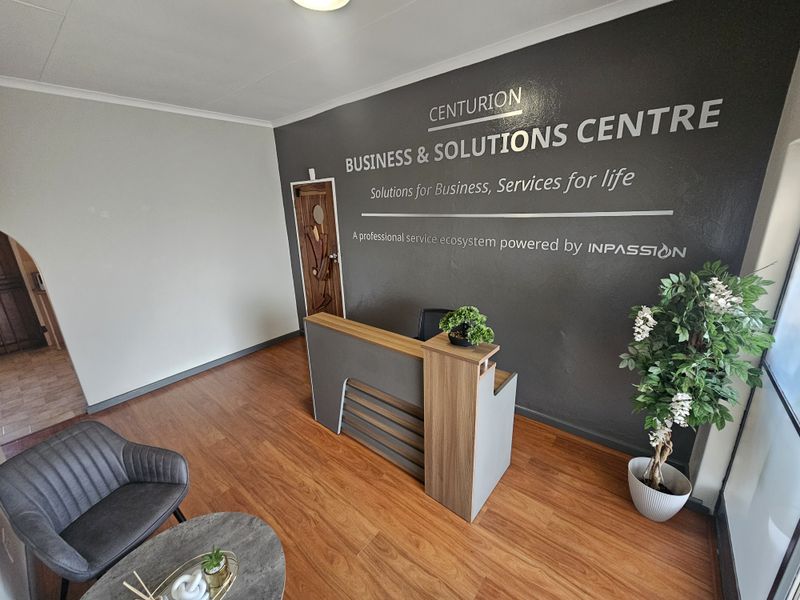 Professional office reception area featuring laminate flooring, a modern reception desk, and a branded feature wall.