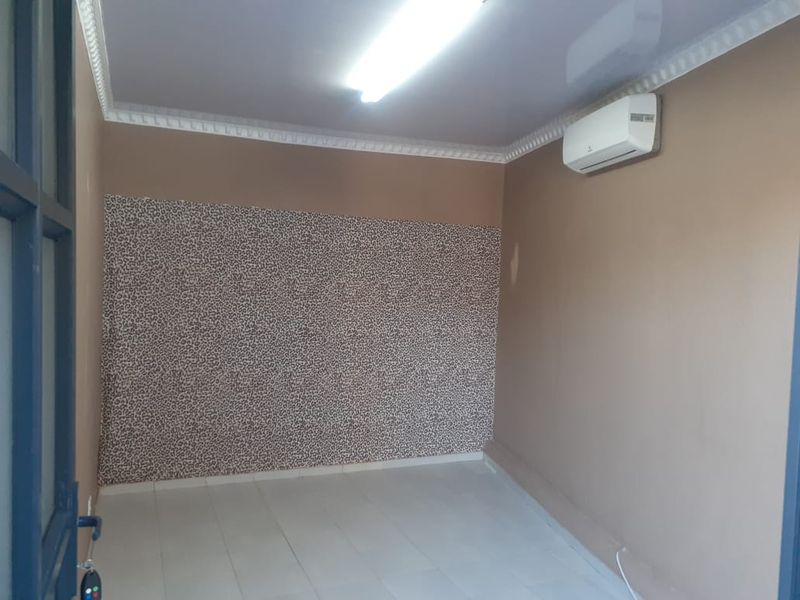 A vacant office space featuring tiled flooring, crown molding, and a wall-mounted split-system air conditioning unit.