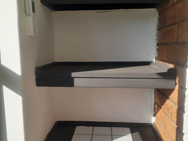 A utility alcove featuring built-in dark painted shelving and exposed brick detailing, suitable for storage or display purposes.