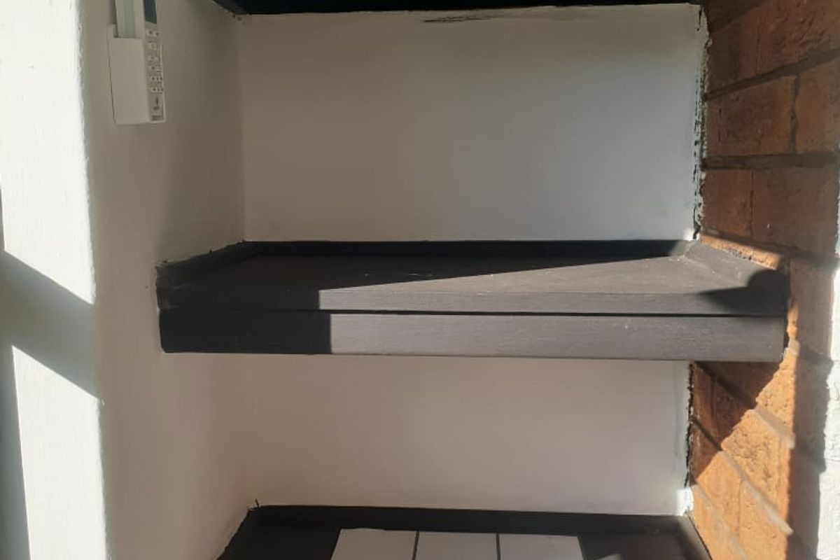 A utility alcove featuring built-in dark painted shelving and exposed brick detailing, suitable for storage or display purposes.