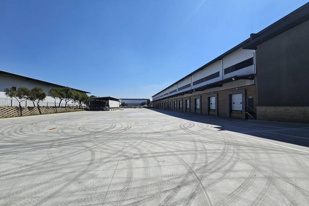 Spacious industrial concrete yard featuring multiple loading docks with roller shutter doors, suitable for logistics and heavy vehicle access.