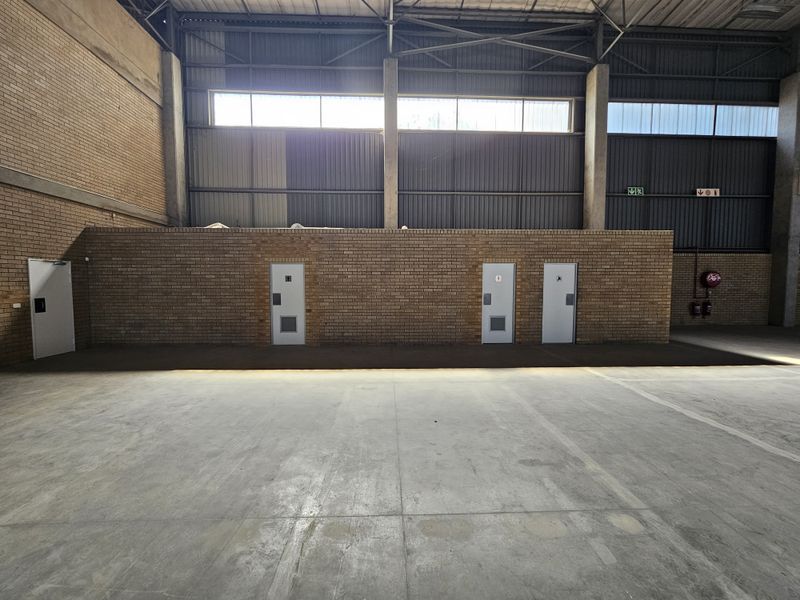 Spacious industrial warehouse interior featuring high ceilings, exposed brick walls, concrete flooring, and multiple access points for operational efficiency.