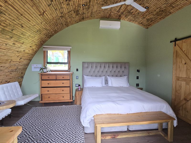 A cozy bedroom featuring a unique vaulted timber ceiling, green accent walls, and a sliding barn door, creating a warm and rustic atmosphere.