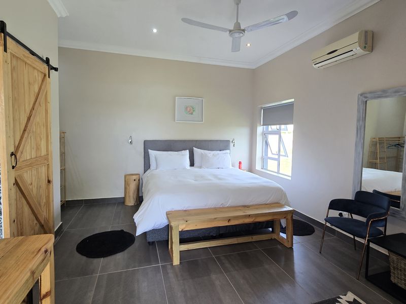 A well-maintained bedroom featuring tiled floors, a sliding barn door, ceiling fan, and integrated air conditioning unit.