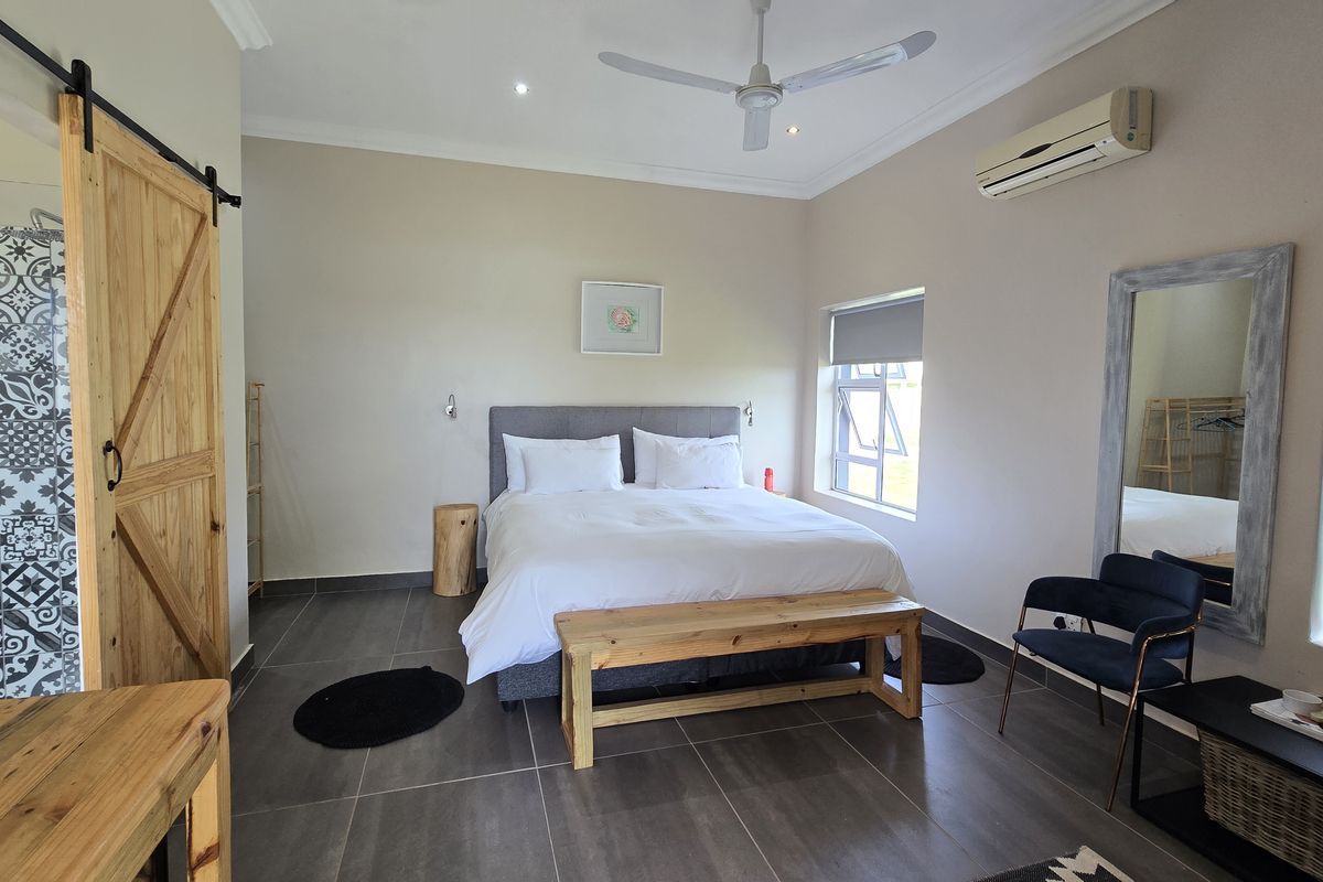 A well-maintained bedroom featuring tiled floors, a sliding barn door, ceiling fan, and integrated air conditioning unit.