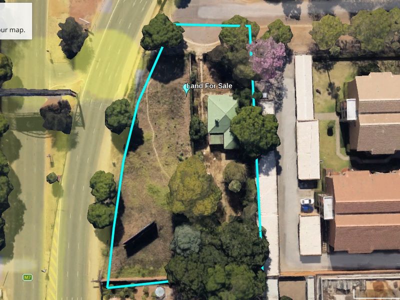 Aerial view of a vacant commercial land plot in Hatfield, featuring established trees and boundary fencing, suitable for development.