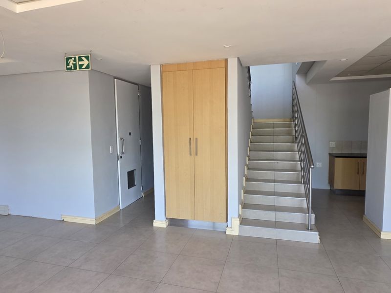 Open plan office space featuring tiled flooring, built-in storage cabinetry, a staircase with metal railing, and recessed lighting.
