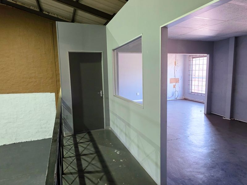 An open-plan industrial office space featuring internal partitioning, security window bars, and exposed roof structure, suitable for a workshop or commercial workspace.