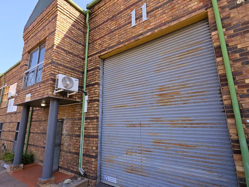 Industrial unit exterior featuring a face brick facade, a large roller shutter door, and an external air conditioning unit.