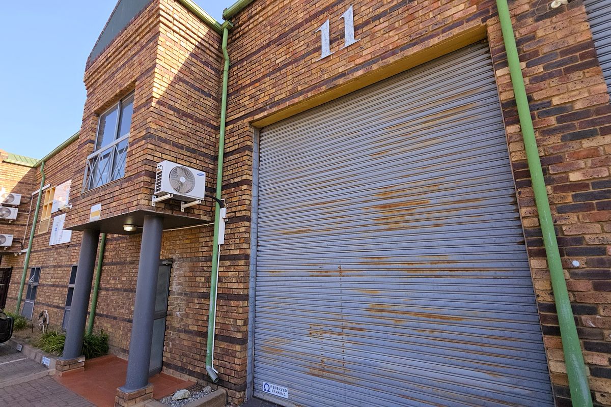 Industrial unit exterior featuring a face brick facade, a large roller shutter door, and an external air conditioning unit.