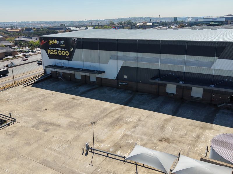 Aerial view of an industrial warehouse facility featuring a large concrete yard, multiple loading docks, and prominent exterior branding.
