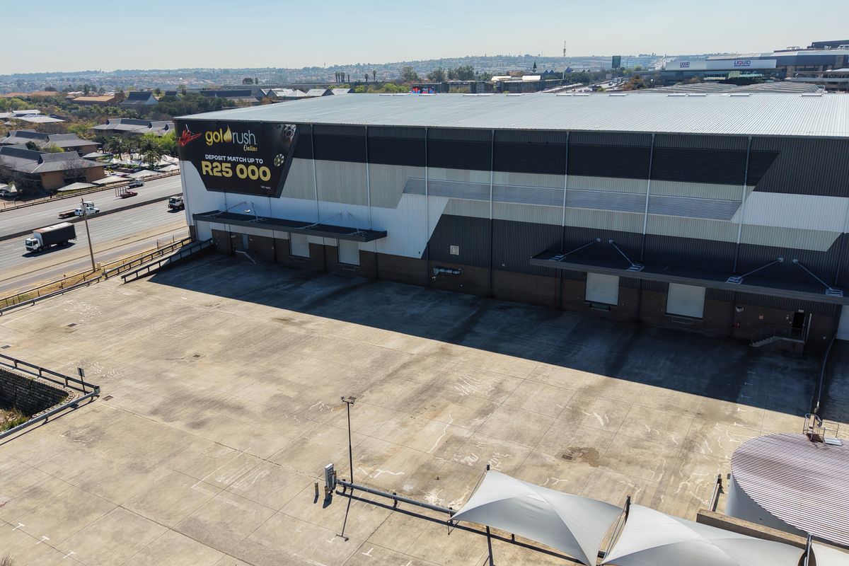 Aerial view of an industrial warehouse facility featuring a large concrete yard, multiple loading docks, and prominent exterior branding.