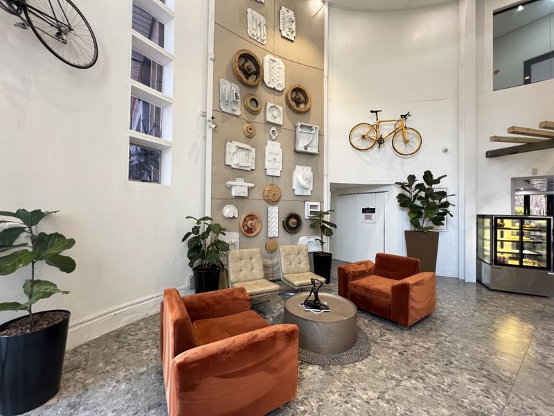 A spacious office reception area featuring high ceilings, terrazzo flooring, and a unique decorative feature wall with integrated vertical windows.