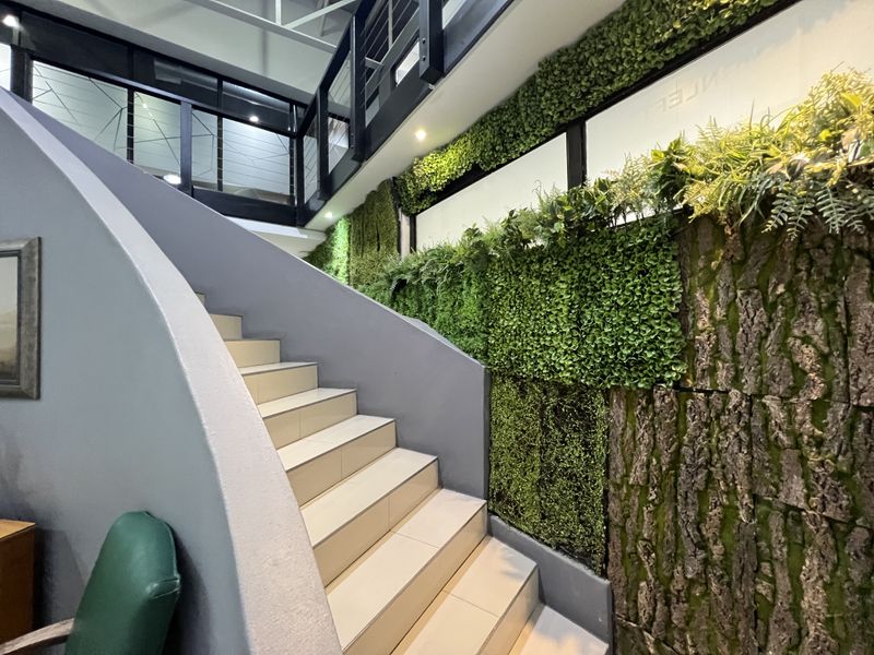 Modern office interior featuring a curved staircase with tiled steps and a striking vertical garden wall feature.