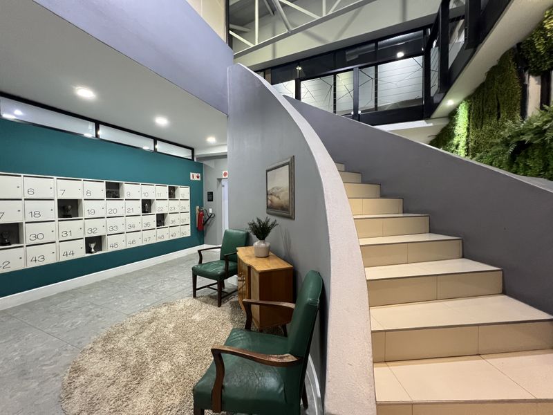 Modern office building entrance featuring a prominent staircase, integrated mailboxes, and a decorative vertical garden wall.