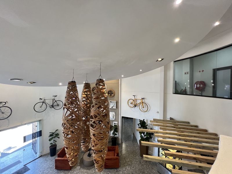 Modern office entrance lobby featuring high ceilings, decorative pendant lighting, stone flooring, and a glass-partitioned office space.