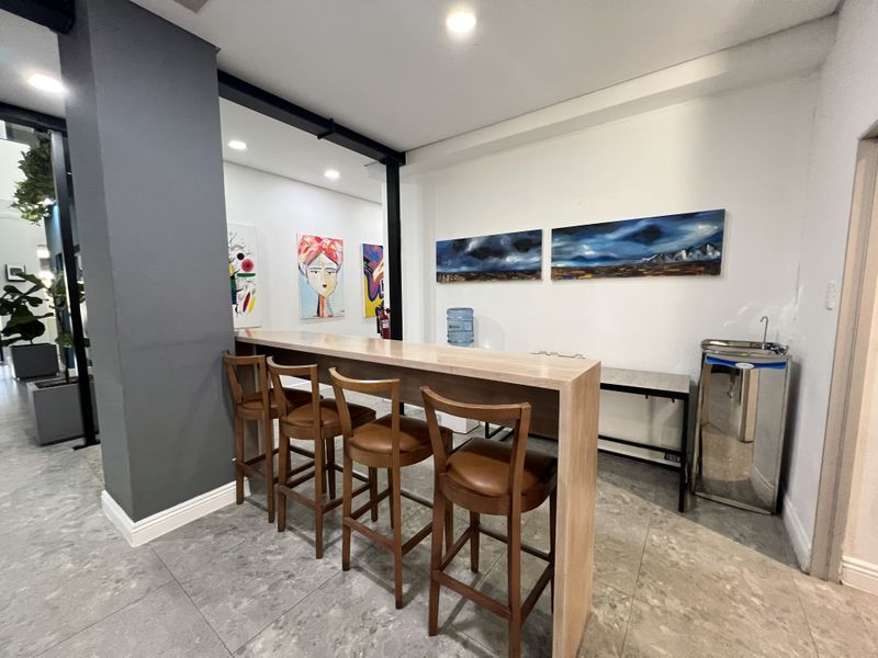 Modern office break area featuring a sleek built-in breakfast bar, recessed lighting, and contemporary tiled flooring in a professional workspace setting.