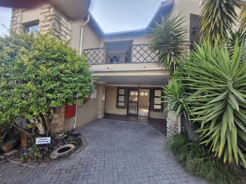 Front entrance of a commercial property featuring a paved driveway, stone accents, and a covered balcony area.