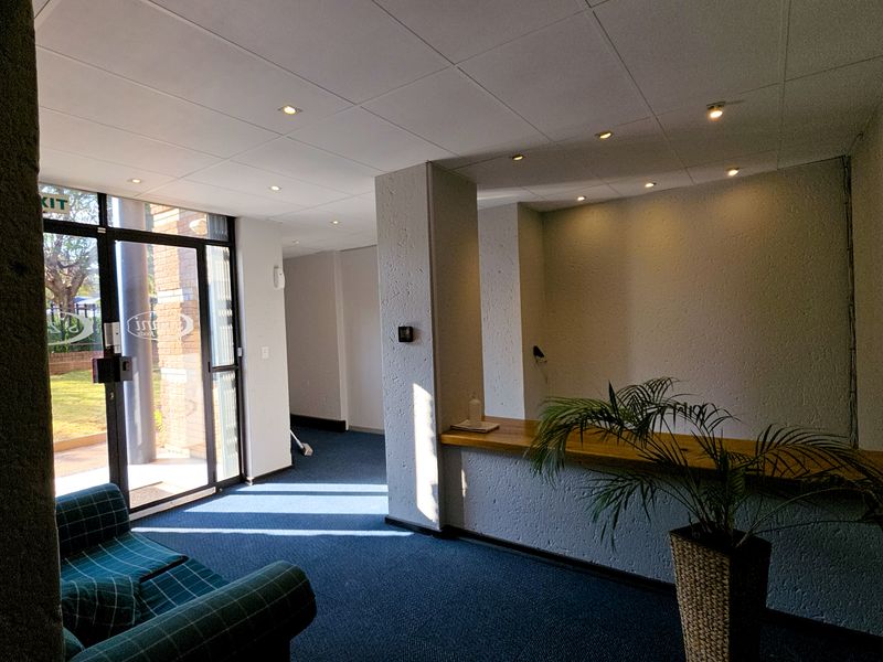 A professional industrial reception area featuring a built-in counter, drop ceiling with recessed lighting, and glass entrance doors leading to the exterior.