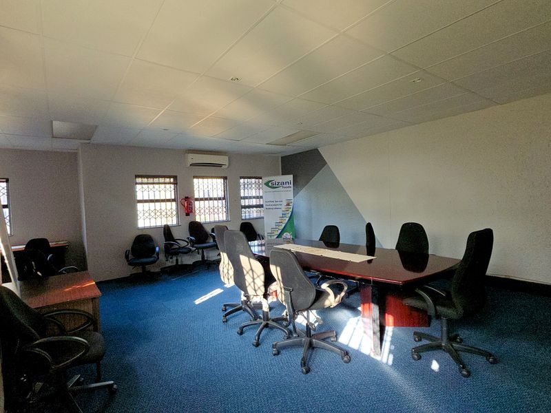A functional office space featuring a suspended ceiling, split-system air conditioning, and security bars on the windows.