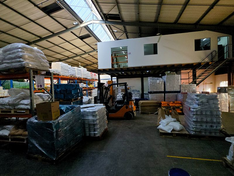 Spacious industrial warehouse featuring a mezzanine level, high-clearance steel frame structure, skylights for natural lighting, and durable concrete flooring.