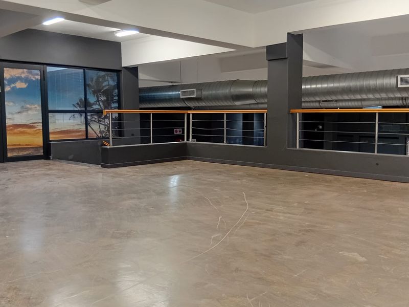Spacious open-plan retail area featuring industrial-style exposed ducting, polished concrete flooring, and modern stainless steel balustrades.