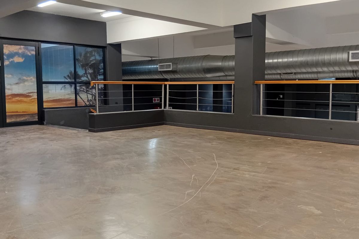 Spacious open-plan retail area featuring industrial-style exposed ducting, polished concrete flooring, and modern stainless steel balustrades.