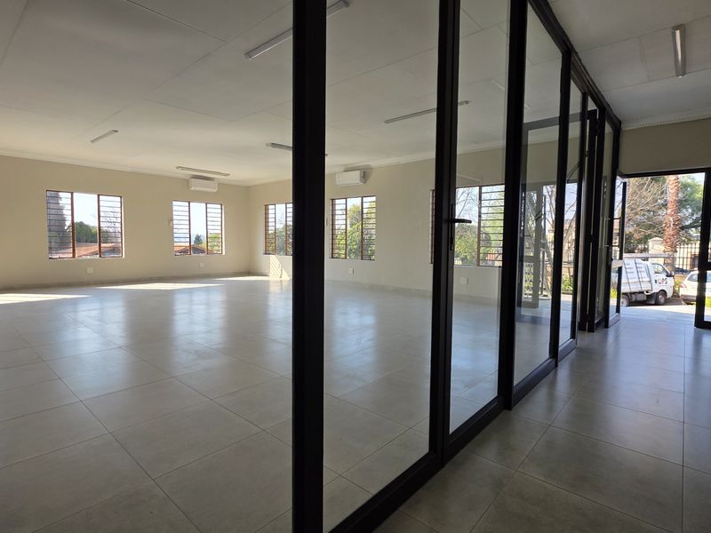 Spacious, open-plan office area featuring large windows, tiled flooring, and modern aluminium-framed glass partitions, providing a bright and professional workspace.