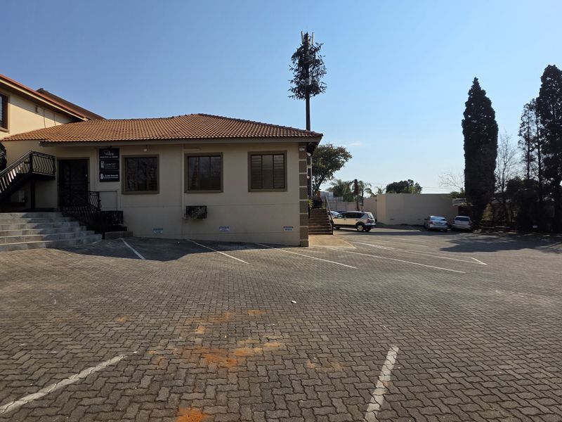 Exterior view of an office building featuring a paved parking area, tiled roof, and external staircase access.