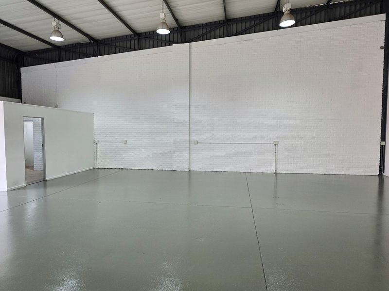 Spacious industrial warehouse unit featuring high ceilings, painted brick walls, durable epoxy flooring, and functional overhead lighting.